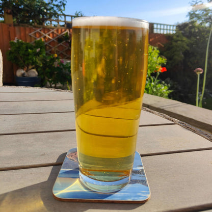 Glass of Kölsch Style All Grain Beer Kit on a wooden table with a garden background